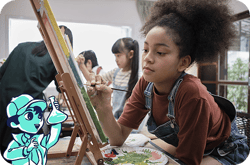 A child paints at an easel during an art activity, with other children in the background and an illustrated water-themed character holding a paintbrush in the corner.